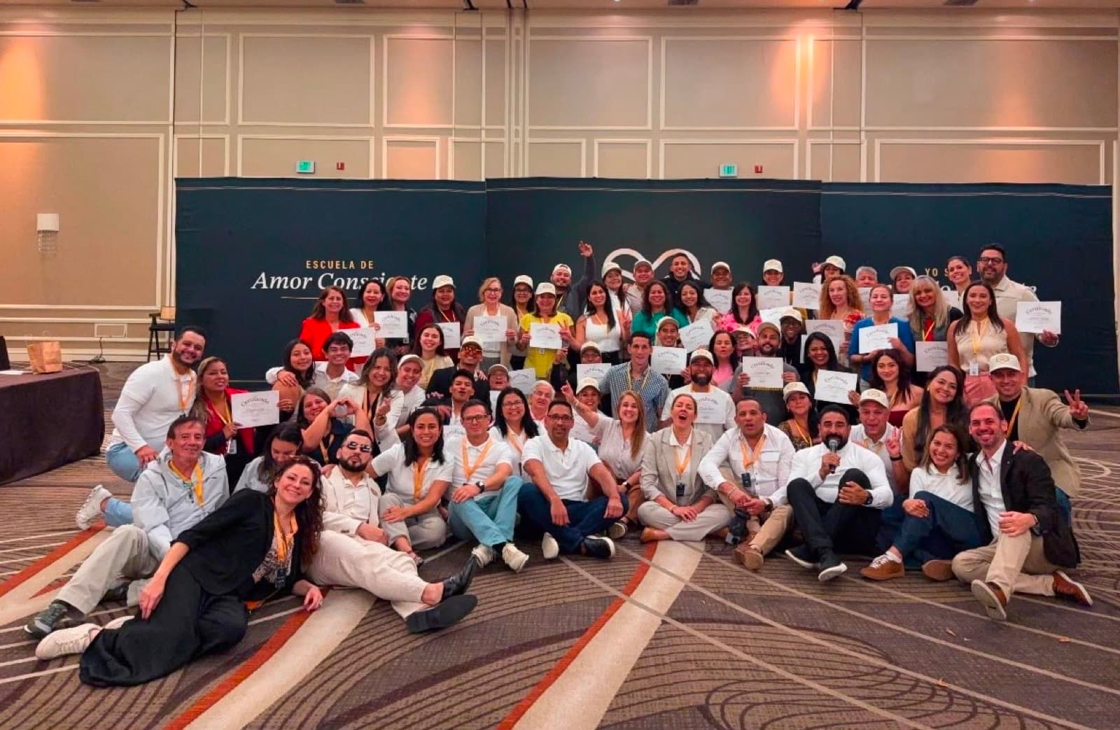 Jairo J. García with a group of graduates holding their certificates in front of the Conscious Love School banner