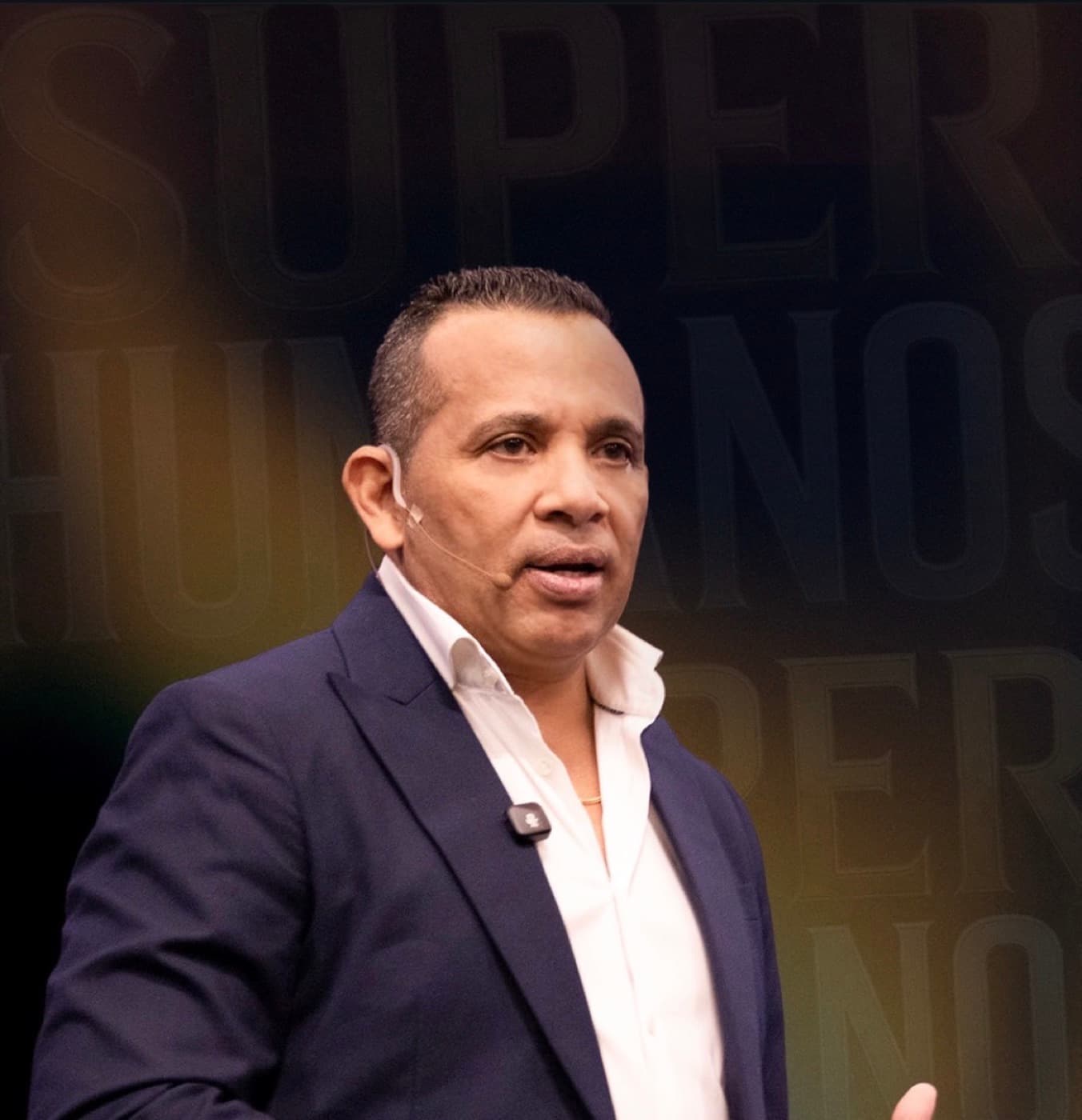 Jairo J. García during a keynote, wearing a headset microphone, in front of a Superhumanos backdrop